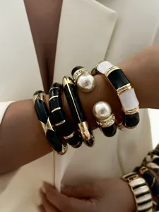 Detail of black and white enamel bangles with gold trim and pearl accents on wrist