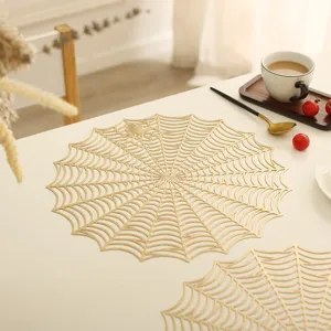 Close-up detail of gold spider web placemat, hollow design perfect for Halloween table decor.