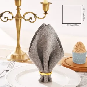 Grey cotton linen dinner napkin with gold napkin ring, exquisite table setting detail view.