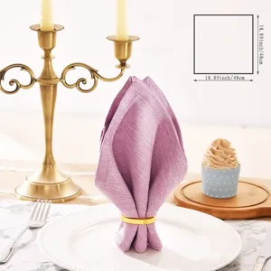 Purple linen napkin folding detail with gold ring on elegant table setting close up