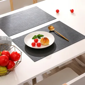 Detail shot of dark gray rectangular PU leather placemat with elegant tableware styling on table.