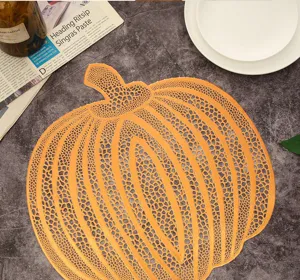Gros plan sur le set de table creux en PVC citrouille dorée, déco de luxe nordique.