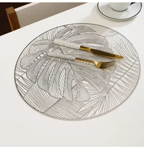 Detail view of PVC monstera leaf placemat with gold foil pattern for dining table decor.