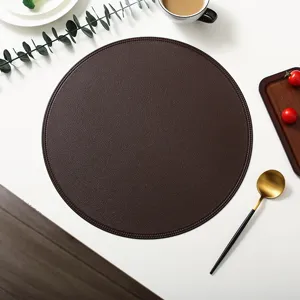 Detailed view of dark brown round leather placemat, featuring exquisite edge stitching, stylish table setting.