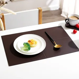 Close-up detail of dark brown leather placemat with elegant grid texture on modern white table.