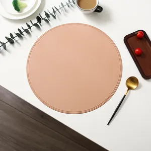 Close-up of a stylish round faux leather placemat on white desk with daily dining props.