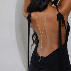 Close-up detail of a delicate gold back chain with crystals on a backless black dress