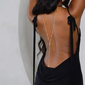 Close-up detail of bohemian gold back chain with shell beads on black backless dress