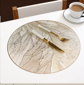 Gedetailleerd overzicht van ronde PVC placemat met verenmotief en gouden bestek voor eettafel.