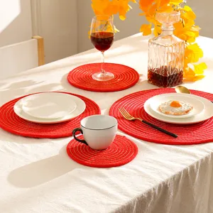 Gedetailleerd scene van rode geweven placemats en onderzetters met gouden draad op eettafel.