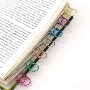 Close-up detail of colorful metal paper clips and pen holders neatly attached on book pages.