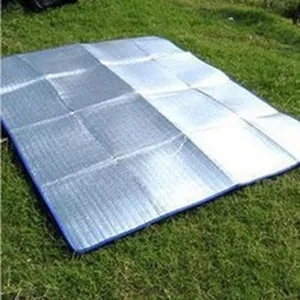 Detail van de outdoor camping picknickmat met zilverkleurige aluminiumfolie op het gras.