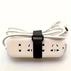 Brida de velcro negra para cables que organiza ordenadamente una regleta eléctrica blanca.