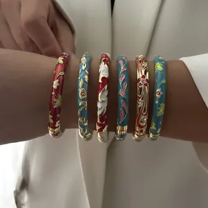 Close-up of six colorful ethnic enamel bangles with floral patterns and gold details