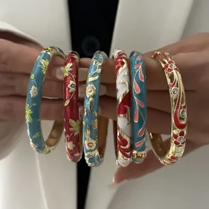 Close-up details of ethnic enamel bangles with intricate flower patterns and gold trim