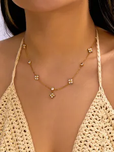Détail d'un collier doré avec des trèfles délicats et des zircons scintillants