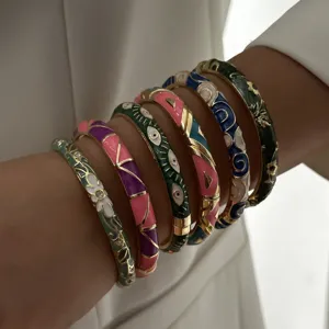 Close-up detail of stacked colorful enamel bangles with floral and evil eye patterns
