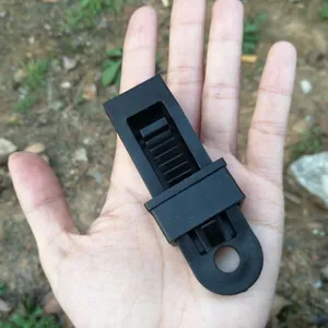 Detail shot of black plastic tent clip, featuring sliding lock design and hanging hole.