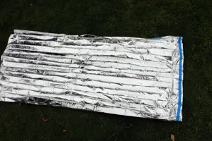 Outdoor emergency survival thermal blanket, silver PE aluminum foil Mylar blanket for use.