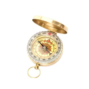 Outdoor vintage brass pocket compass with flip cover and luminous dial for navigation.