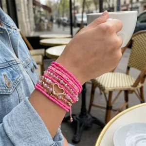 Detailansicht eines pinkfarbenen Perlenarmband-Sets mit einem goldenen Herz-Anhänger