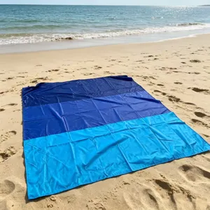 Detailed view of waterproof blue beach mat spread on sandy shore near sea waves.