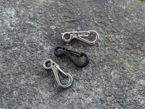 Nahaufnahme von Mini-Federhaken in drei Farben, ideal als EDC-Schluesselanhaenger.