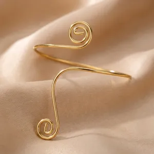 Detailed view of a golden minimalist geometric spiral open metal arm cuff on silk