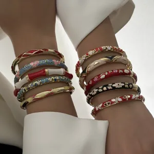 Detailed close-up of ethnic style enamel floral bangles stacked on a model's arms.