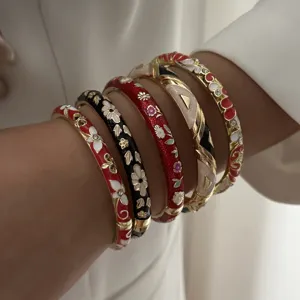 Elegant ethnic style enamel bangles with flower patterns worn on a woman's wrist