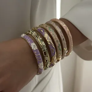 Close-up detail of layered ethnic enamel floral bangles with intricate gold patterns