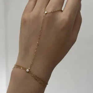 Détail d'un bracelet de main minimaliste en acier doré avec des pierres transparentes