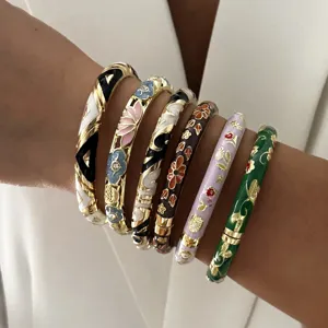 Detailed view of stacked ethnic floral enamel bangles on a woman's wrist