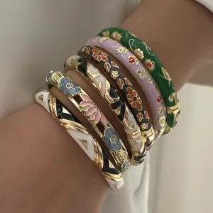 Close-up of a stack of six colorful ethnic enamel floral bracelets on a model wrist detail