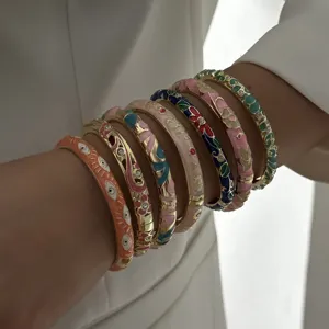 Detail view of ethnic enamel floral bangles with colorful patterns and gold accents