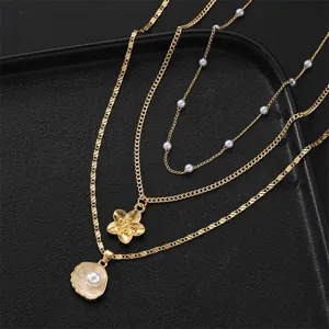 Close-up of three-layered gold necklace with decorative shell and flower pendants