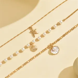 Macro view of a multi-layer beach necklace featuring golden starfish and shell pendants