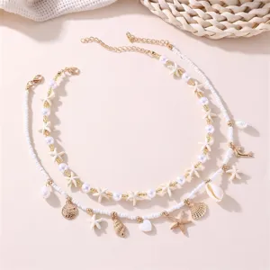 Detail of layered beach-style necklace with starfish, shells, and white beads.