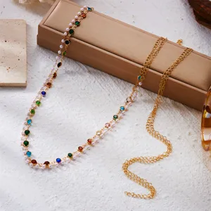 Detail view of a colorful rhinestone and pearl layered gold metal beach body chain