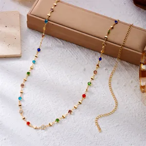 Close-up detail of a golden beach body chain featuring vibrant multi-colored rhinestones.
