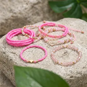 Detailaufnahme eines 10-teiligen pinkfarbenen Perlenarmband-Sets mit Herzanhänger