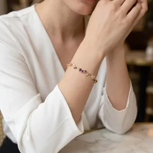 Close-up of elegant gold floral bracelet with purple gems on model's wrist