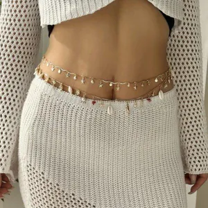 Close-up of golden body chain with delicate sea shell and starfish pendant charms
