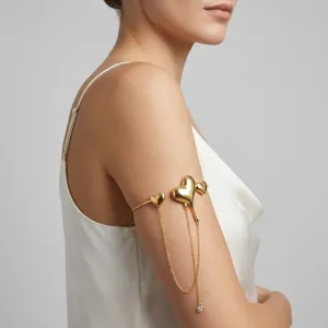 Close-up detail of a gold arm cuff featuring heart shapes and delicate dangling chains