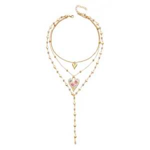 Detailed view of a multilayered gold heart necklace with a colorful enamel pendant