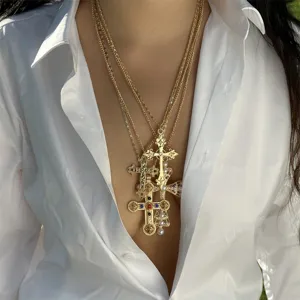 Close-up of layered gold cross necklaces with pearls and colorful rhinestones on a model