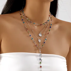 Macro view of layered silver necklaces with colorful rhinestones and religious charms