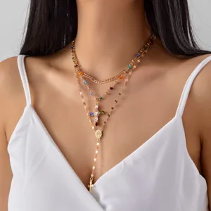 Detailed view of layered gold necklace with colorful rhinestones and cross pendant