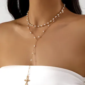 Layered gold cross necklace with pearls on model, elegant jewelry detail