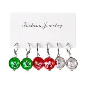 Gros plan sur trois paires de boucles d'oreilles boules de Noël en acrylique avec motifs variés